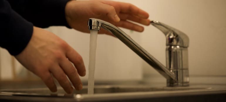 A person using an eco-friendly low-flow faucet in their bathroom